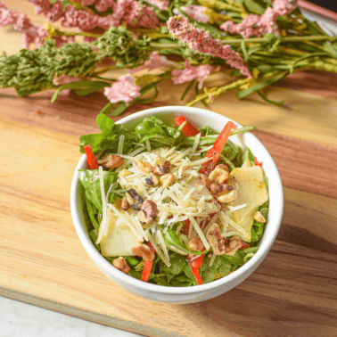 A picture of a white bowl containing a cannabis pear and arugula salad.