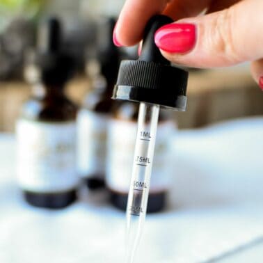 A hand holding a dropper for CBD.